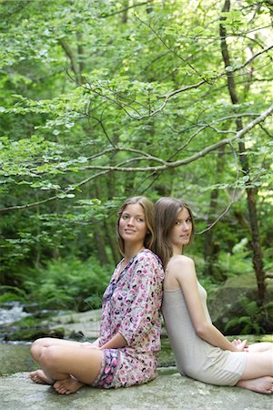 female friends sitting on ground - Female friends sitting back to back on rock, portrait Stock Photo - Premium Royalty-Free, Code: 633-05401818