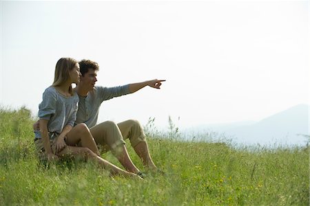 field, man - Couple sitting on meadow, man pointing toward distance Stock Photo - Premium Royalty-Free, Code: 633-05401830