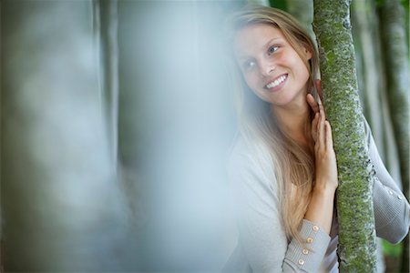 simsearch:633-05401416,k - Young woman leaning against tree trunk, focus on background Stock Photo - Premium Royalty-Free, Code: 633-05401832