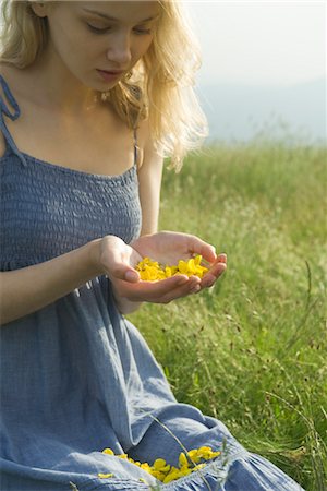 simsearch:633-05401416,k - Young woman sitting in field, holding flower petals in cupped hands Stock Photo - Premium Royalty-Free, Code: 633-05401851