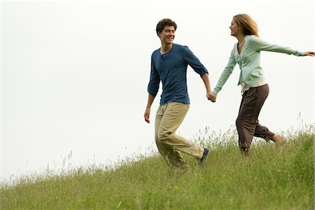 Couple holding hands running on meadow Stock Photo - Premium Royalty-Free, Code: 633-05401900