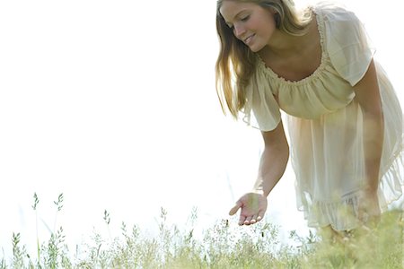 simsearch:633-05402126,k - Young woman bending over to touch tall grass Stock Photo - Premium Royalty-Free, Code: 633-05401911