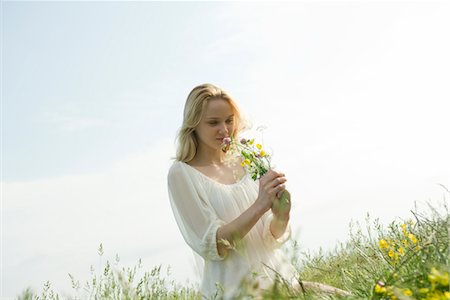 fragrance - Young woman sitting in field of wildflowers, smelling bouquet Stock Photo - Premium Royalty-Free, Code: 633-05401923