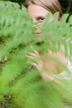 simsearch:633-06406668,k - Woman peeking through fern frond, portrait Stock Photo - Premium Royalty-Free, Code: 633-05401985