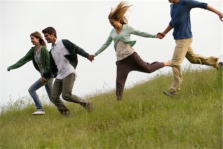 friends smiling group - Young adults running on meadow holding hands Stock Photo - Premium Royalty-Free, Code: 633-05402155