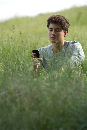 simsearch:400-08997106,k - Young man sitting in grass text messaging Stock Photo - Premium Royalty-Free, Code: 633-05402156