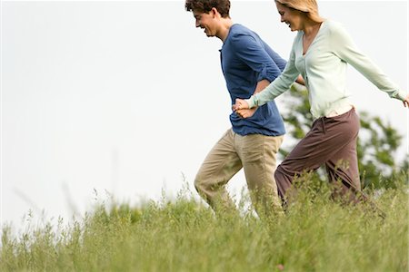 Couple holding hands walking on meadow Stock Photo - Premium Royalty-Free, Code: 633-05402188