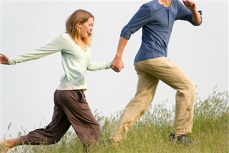 Young woman running on meadow with boyfriend Stock Photo - Premium Royalty-Free, Code: 633-05402216