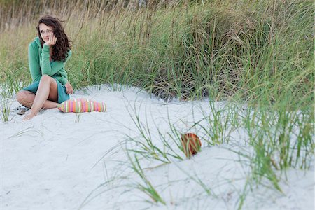 Teenage girl sitting alone on beach, smiling Stock Photo - Premium Royalty-Free, Code: 633-06322214