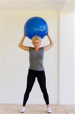 exercising indoors one - Mature woman holding up fitness ball behind head Stock Photo - Premium Royalty-Free, Code: 633-06322293