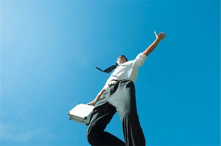 Homme d'affaires de sauter dans l'air transportant des porte-documents, vue d'angle faible Photographie de stock - Premium Libres de Droits, Code: 633-06322617