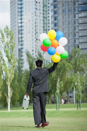 Businessman walking with bunch of balloons, rear view Stock Photo - Premium Royalty-Free, Code: 633-06322668