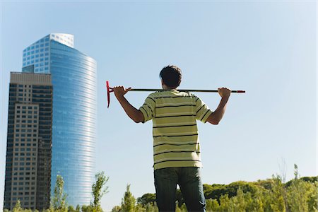 Farmer standing in field, contemplating skyscrapers Stock Photo - Premium Royalty-Free, Code: 633-06355039