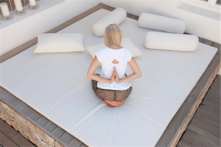 picture of woman kneeling down from behind - Woman doing reverse prayer pose on bed in patio, rear view Stock Photo - Premium Royalty-Free, Code: 633-06406339