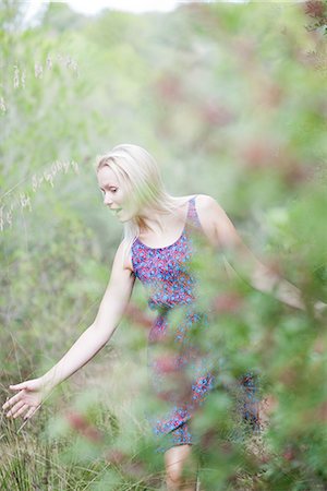 Young woman walking in nature, touching tall grass Stock Photo - Premium Royalty-Free, Code: 633-06406396