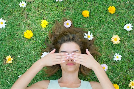simsearch:633-06406668,k - Woman lying on grass surrounded by flowers with hands covering eyes Stock Photo - Premium Royalty-Free, Code: 633-06406456