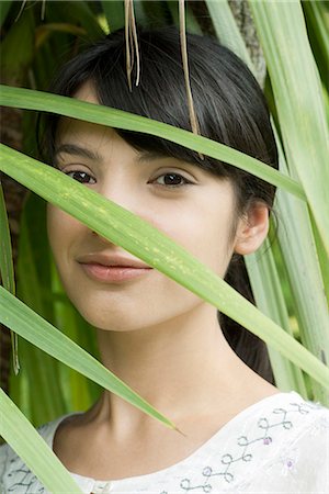 simsearch:633-06406668,k - Young woman looking through foliage, portrait Stock Photo - Premium Royalty-Free, Code: 633-06406464