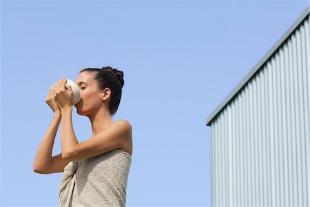 Mid-adult woman wrapped in towel drinking from bowl, side view Stock Photo - Premium Royalty-Free, Code: 633-06406541