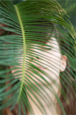 simsearch:633-06406668,k - Young woman behind palm frond, eyes closed Stock Photo - Premium Royalty-Free, Code: 633-06406587
