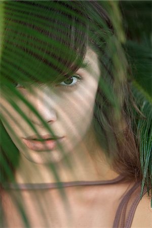 simsearch:633-06406668,k - Young woman behind palm frond, portrait Stock Photo - Premium Royalty-Free, Code: 633-06406739