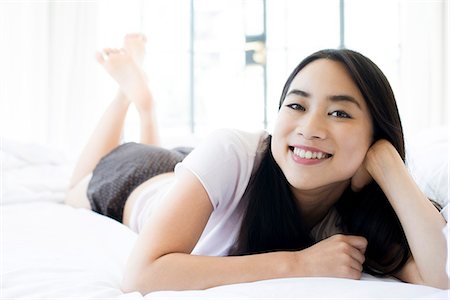 simsearch:632-06030123,k - Woman lying on bed, smiling cheerfully Fotografie stock - Premium Royalty-Free, Codice: 633-08482076