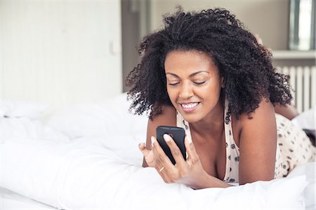 simsearch:6109-08953148,k - Woman using cell phone on bed Stock Photo - Premium Royalty-Free, Code: 633-08639053