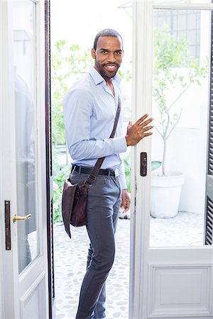 simsearch:632-05604578,k - Man standing in open doorway, smiling, portrait Photographie de stock - Premium Libres de Droits, Code: 633-08726181