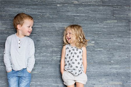 simsearch:632-08227559,k - Children leaning against wall, smiling at each other Stock Photo - Premium Royalty-Free, Code: 633-08726287