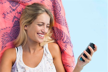 relaxing in lounge chair - Woman streaming video on smartphone while lounging by pool Stock Photo - Premium Royalty-Free, Code: 633-08726329