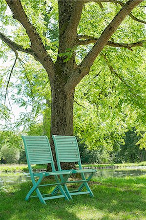 simsearch:633-08150944,k - Chairs arranged beneath a tree at water's edge Photographie de stock - Premium Libres de Droits, Code: 633-08726320