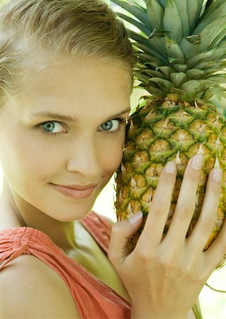 pineapple growing - Woman holding pineapple next to face, smiling at camera Stock Photo - Premium Royalty-Free, Code: 633-01274125