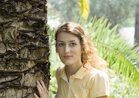 simsearch:633-05402143,k - Femme se tenant avec une main sur le tronc de l'arbre, souriant à la caméra Photographie de stock - Premium Libres de Droits, Code: 633-01274163