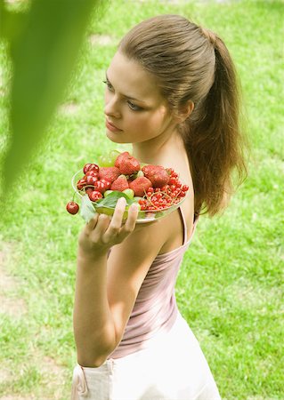 strawberries many - Young woman holding up bowl of fruit Stock Photo - Premium Royalty-Free, Code: 633-01274250