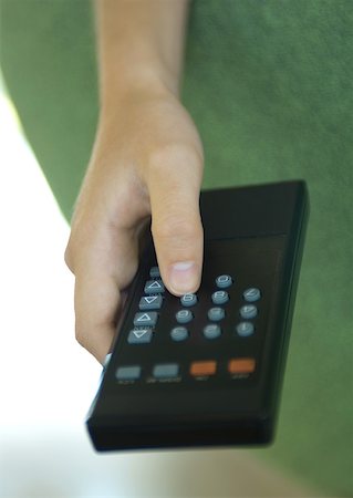 Hand pressing button on remote control Stock Photo - Premium Royalty-Free, Code: 633-01274504