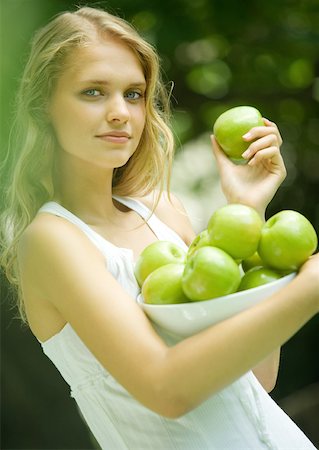 simsearch:633-01272776,k - Woman holding bowl of apples, smiling at camera Foto de stock - Royalty Free Premium, Número: 633-01274674