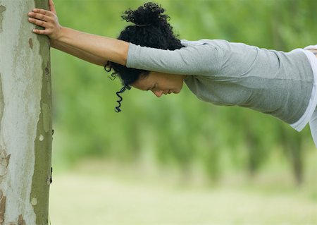 simsearch:633-01714395,k - Young woman stretching against tree trunk Foto de stock - Sin royalties Premium, Código: 633-01274673