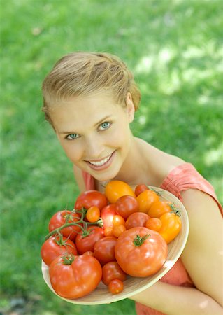 simsearch:633-01272776,k - Young woman holding up bowl of tomatoes, smiling at camera Foto de stock - Royalty Free Premium, Número: 633-01275011