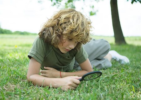 Boy lying in grass with magnifying glass Stock Photo - Premium Royalty-Free, Code: 633-01275070