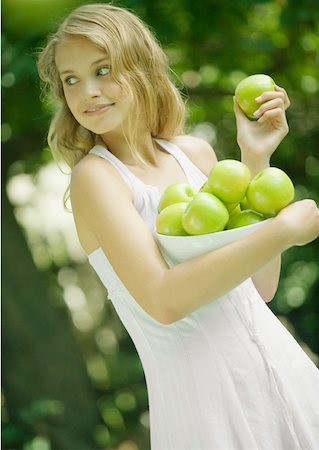 simsearch:633-01272776,k - Woman holding bowl of apples, looking over shoulder Foto de stock - Royalty Free Premium, Número: 633-01272095