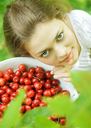 simsearch:633-01272776,k - Woman holding bowl of cherries, smiling at camera Foto de stock - Royalty Free Premium, Número: 633-01272268