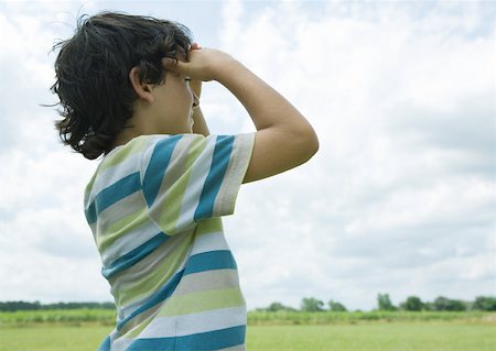 Boy shading eyes, looking into distance Stock Photo - Premium Royalty-Free, Code: 633-01272297