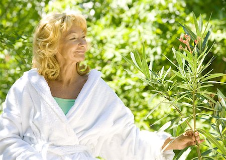 rose bay - Senior woman in bathrobe smiling and examining branch of shrub Foto de stock - Royalty Free Premium, Número: 633-01272320