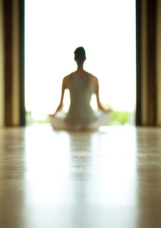 Yoga class, woman sitting in lotus position, defocused and backlit Stock Photo - Premium Royalty-Free, Code: 633-01272755