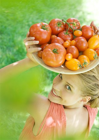 simsearch:633-02231743,k - Young woman holding up bowl of tomatoes, smiling at camera Stock Photo - Premium Royalty-Free, Code: 633-01272795