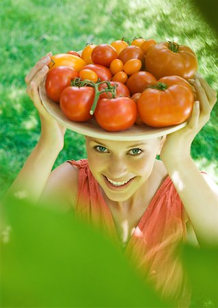 simsearch:633-01272776,k - Young woman holding up bowl of tomatoes, smiling at camera Foto de stock - Royalty Free Premium, Número: 633-01272984