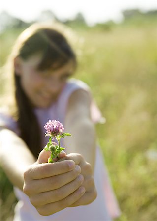 Girl holding out flower, focus on flower in foreground Stock Photo - Premium Royalty-Free, Code: 633-01273099