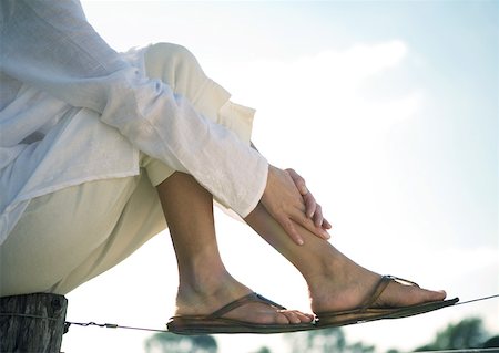 flip flops close - Woman sitting on wooden post resting feet on wire Stock Photo - Premium Royalty-Free, Code: 633-01273332