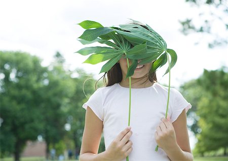 Girl standing holding cassava leaves in front of face Foto de stock - Sin royalties Premium, Código: 633-01273711