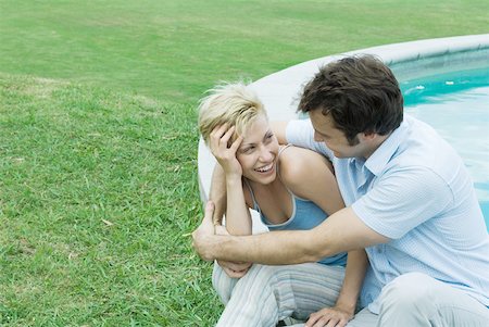 simsearch:632-03779625,k - Couple sitting by pool, smiling at each other Stock Photo - Premium Royalty-Free, Code: 633-01574058