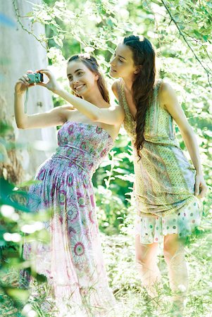 simsearch:632-05553991,k - Two young women wearing sun dresses, standing in forest, taking photo with digital camera Stock Photo - Premium Royalty-Free, Code: 633-01574158